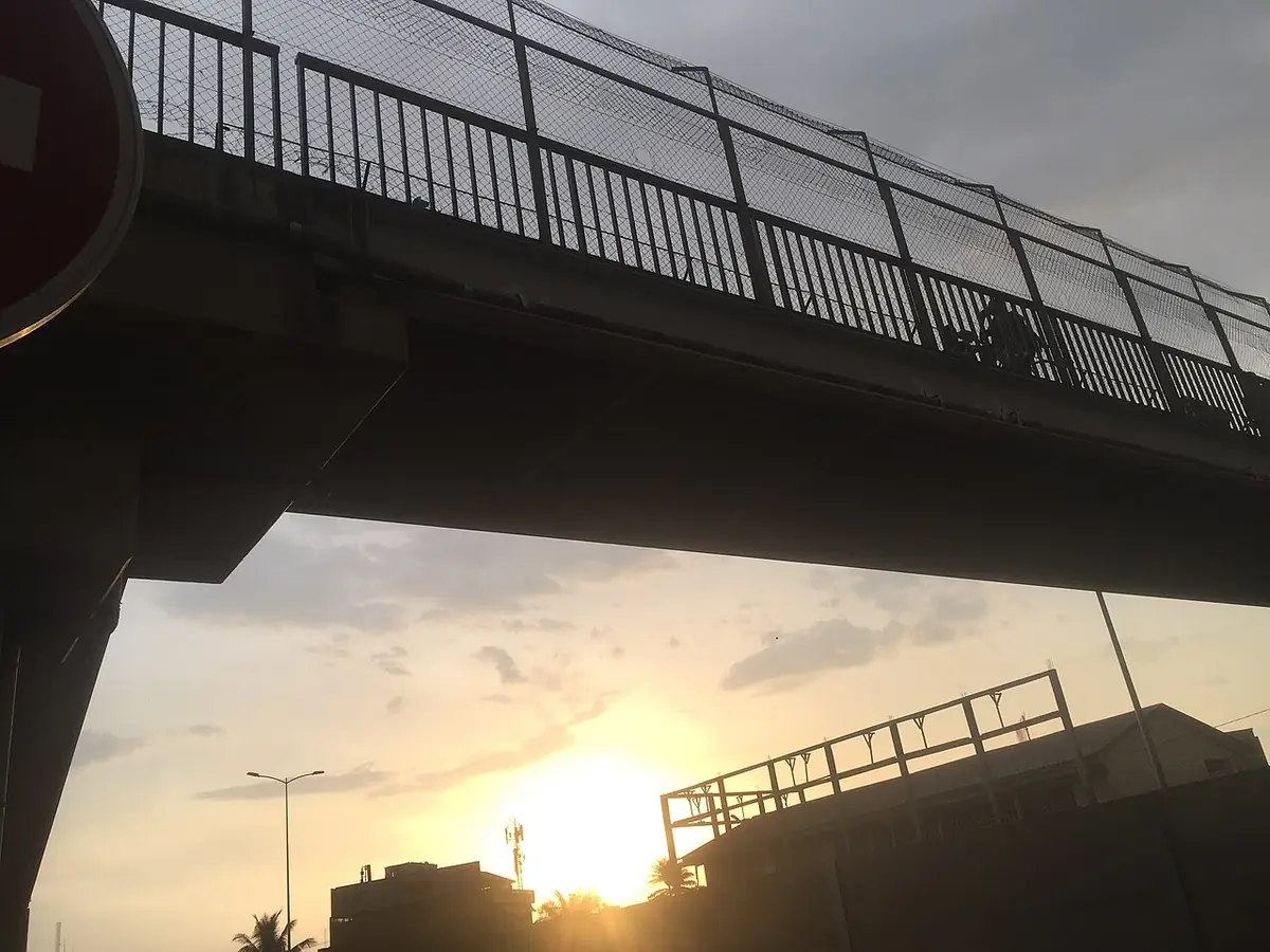 Un pont piéton se découpant sur le coucher de soleil à Abidjan