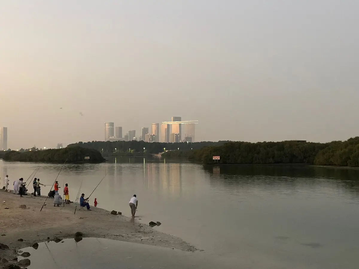 Pêcheurs au bord de l’eau à Eastern Mangroves, mangrove et tours au loin dans la brume