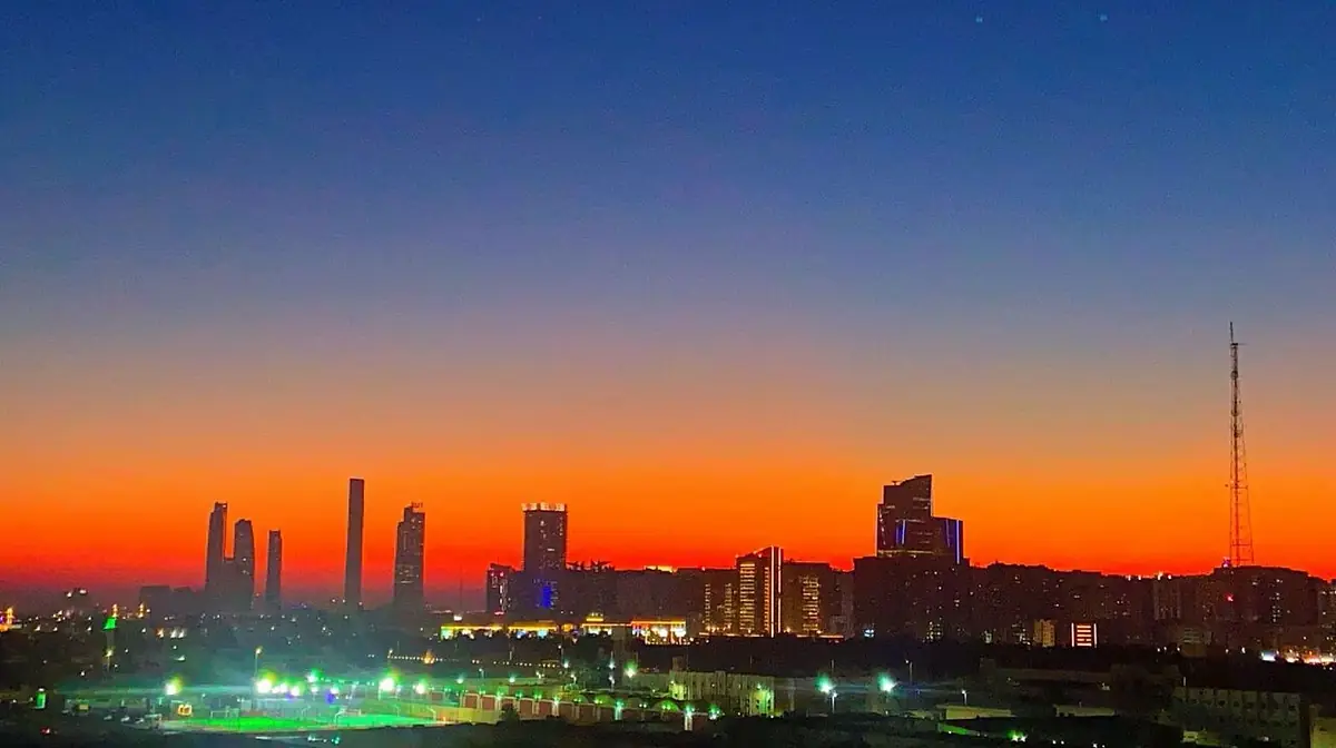 Abu Dhabi's skyline silhouetted against an orange sunset sky