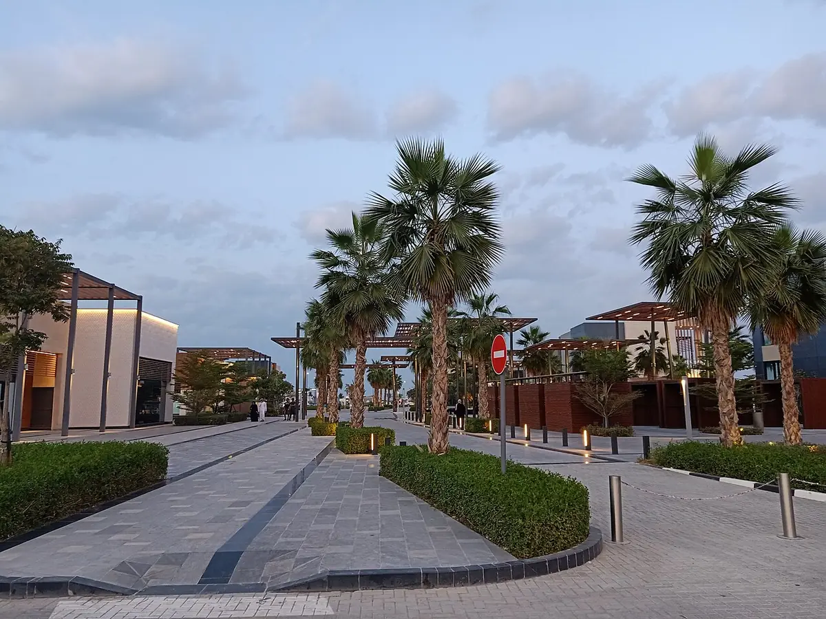 Une promenade bordée de palmiers à Al Marsa, à Ajman, menant vers l’eau