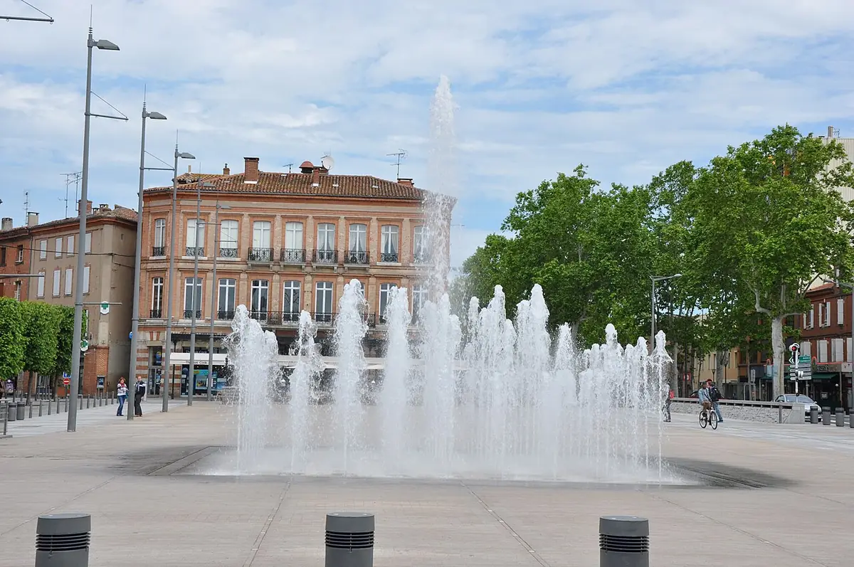 Une fontaine sur la place du Vigan à Albi avec des passants