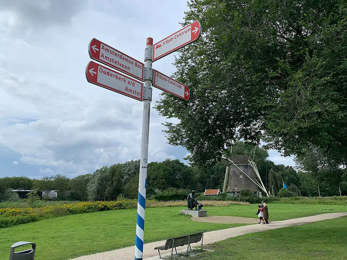 Un parc d’Amsterdam avec un moulin miniature et un panneau directionnel