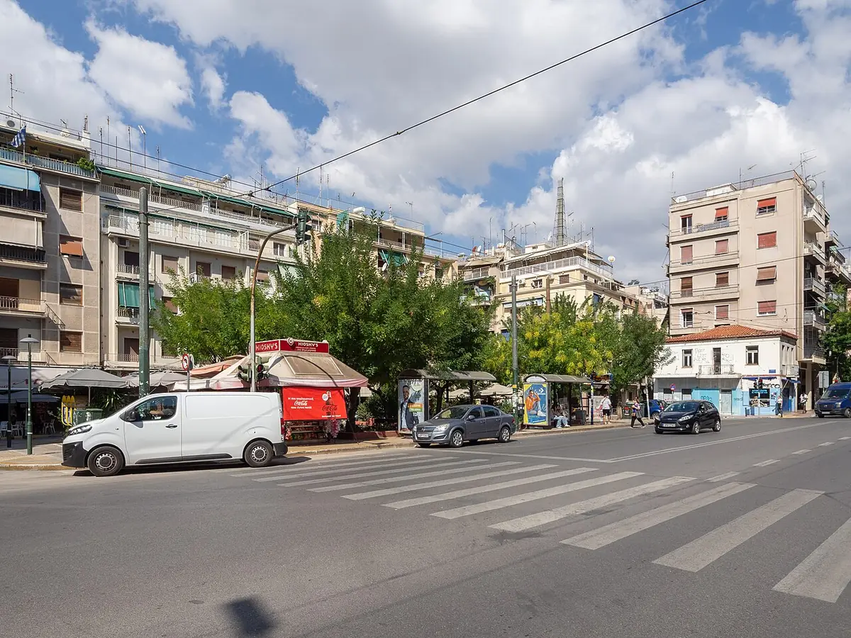 La place Koliatsou, avec ses arbres, un kiosque et des immeubles autour d’un carrefour