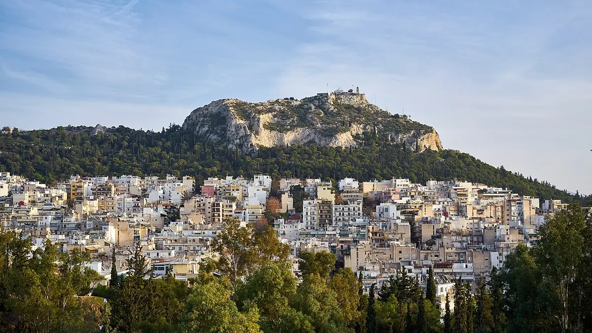 Le mont Lycabette dominant les immeubles d’Athènes sous un ciel bleu