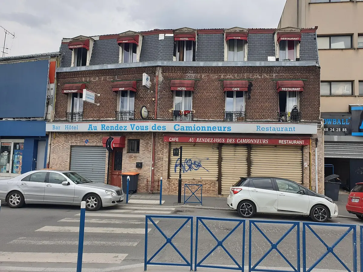 Un café-restaurant à l’angle d’une rue à Aubervilliers, façade rouge typique