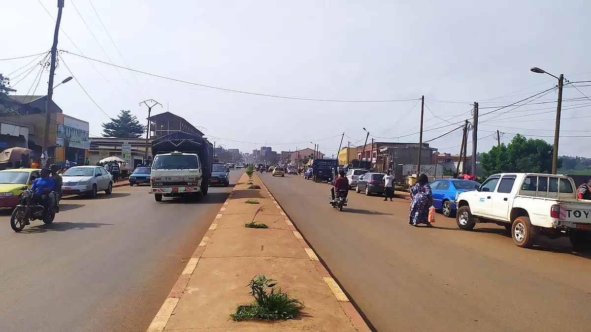 Une avenue de Bafoussam avec terre-plein central, circulation de motos et véhicules