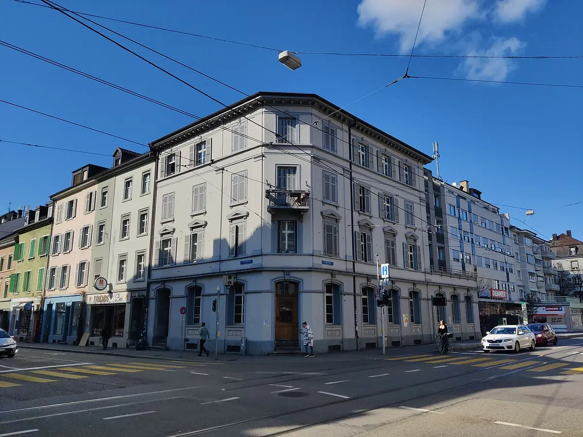 Un immeuble d’angle à Bâle, façade blanche classique sur rue commerçante