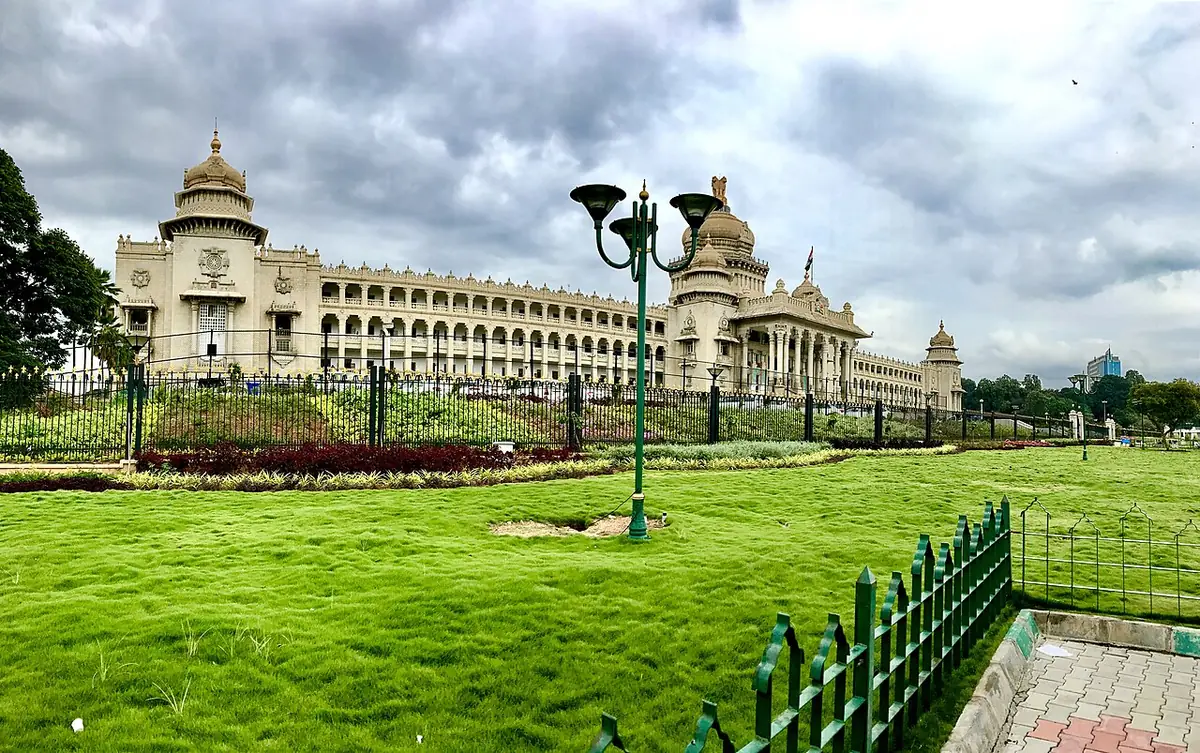 Panorama du Vidhana Soudha à Bangalore derrière des pelouses paysagées, sous un ciel nuageux