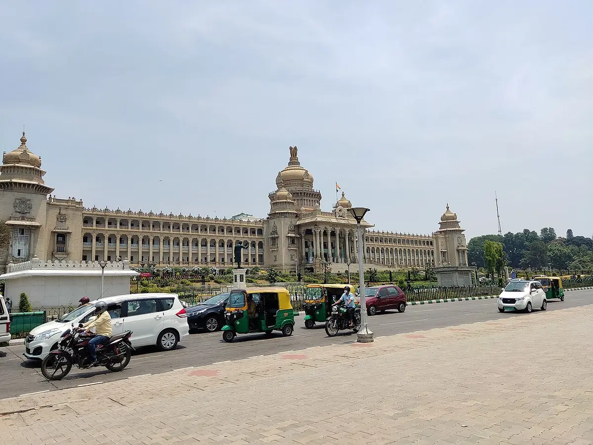 Rickshaws, voitures et motos sur une large avenue devant le Vidhana Soudha, à Bangalore