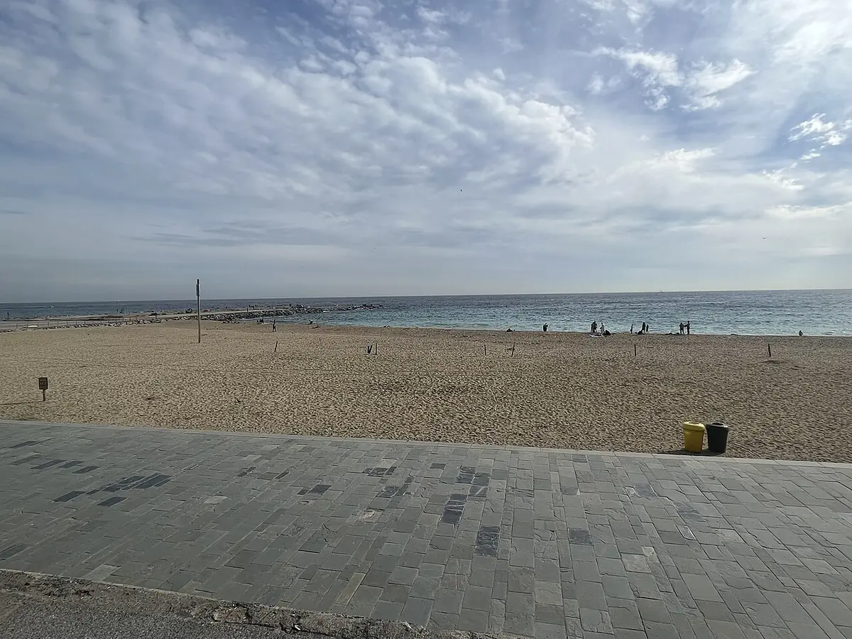 La promenade de la plage du Bogatell à Barcelone, sable et ciel nuageux