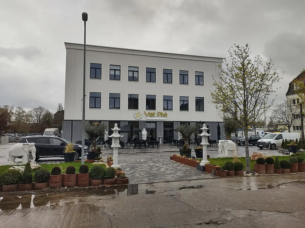 Une place avec restaurant en terrasse et façade blanche à Berlin