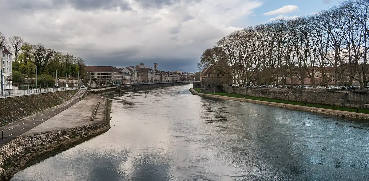 Le Doubs à Besançon sous un ciel nuageux, silhouette de la ville au loin