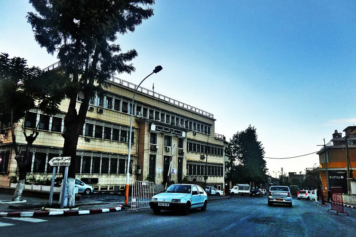 Une rue de Blida bordée d’un grand bâtiment institutionnel