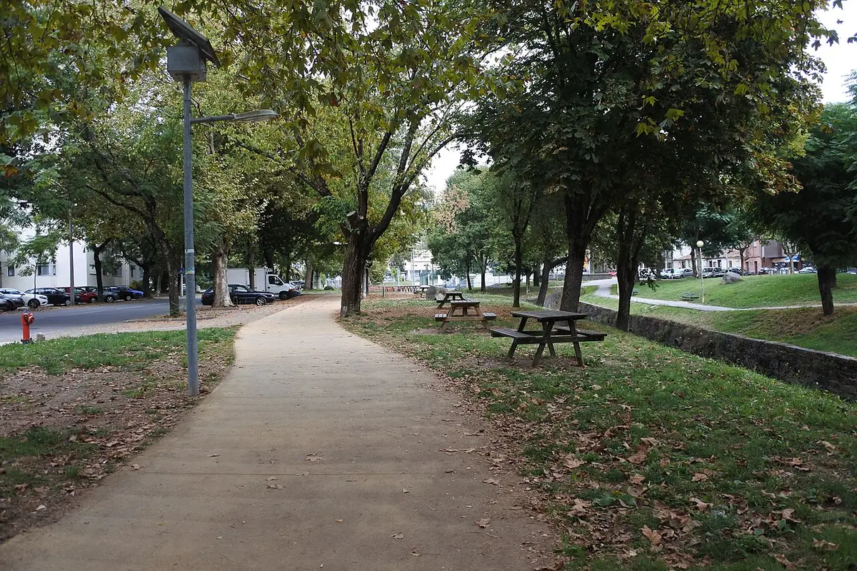 Une allée arborée le long de la rivière à Braga, avec un banc public