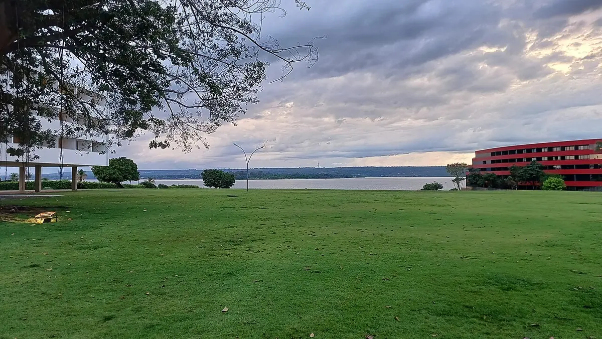 Une grande étendue d’herbe verte au bord du lac, sous un ciel nuageux à Brasília