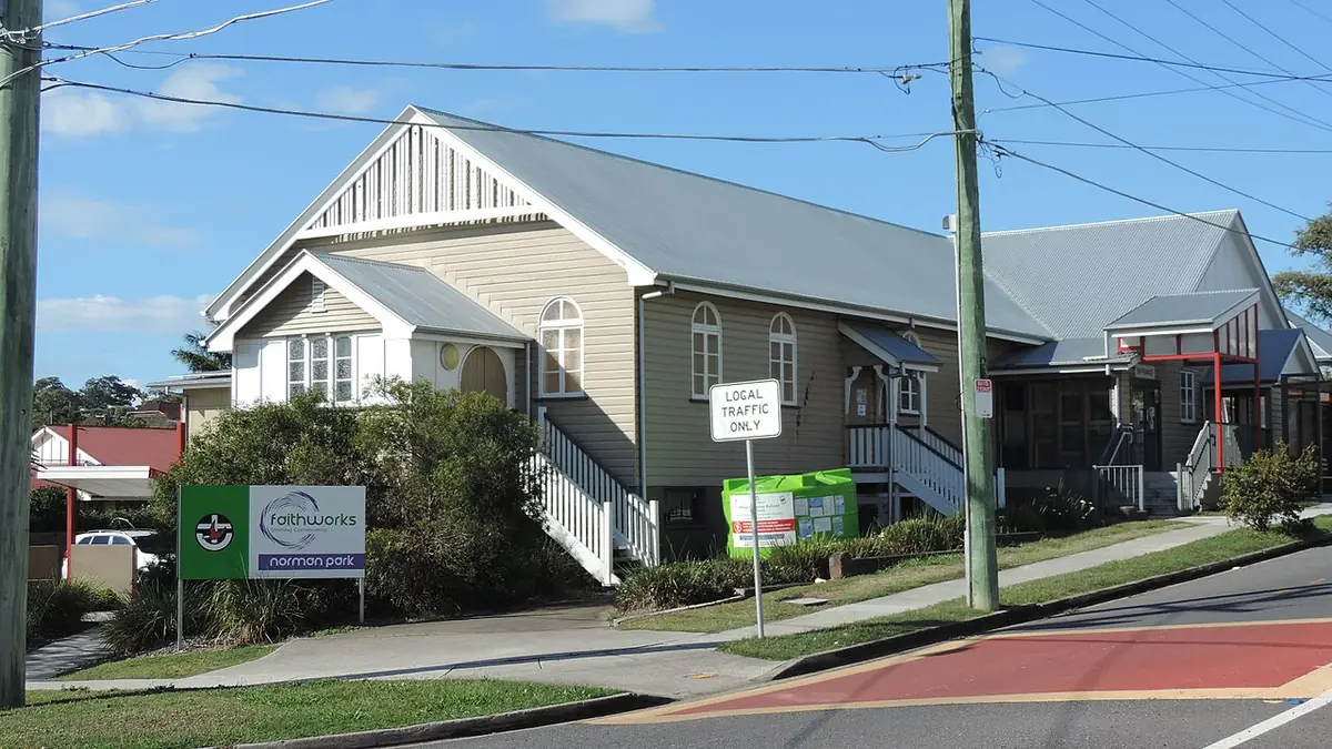 L'église en bois de Norman Park, au toit en pente, à l'angle d'une rue résidentielle ensoleillée de Brisbane