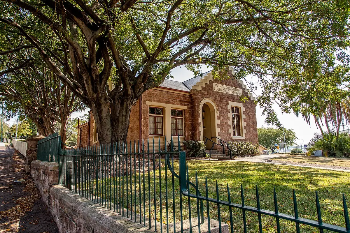 L'ancien conseil municipal de Windsor, en briques, derrière une clôture et de grands arbres, à Brisbane
