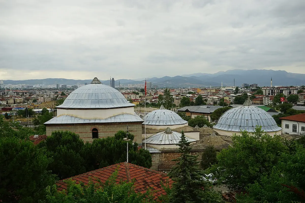 Toits en coupole du hamam Yeni Kaplıca surplombant Bursa sous un ciel nuageux