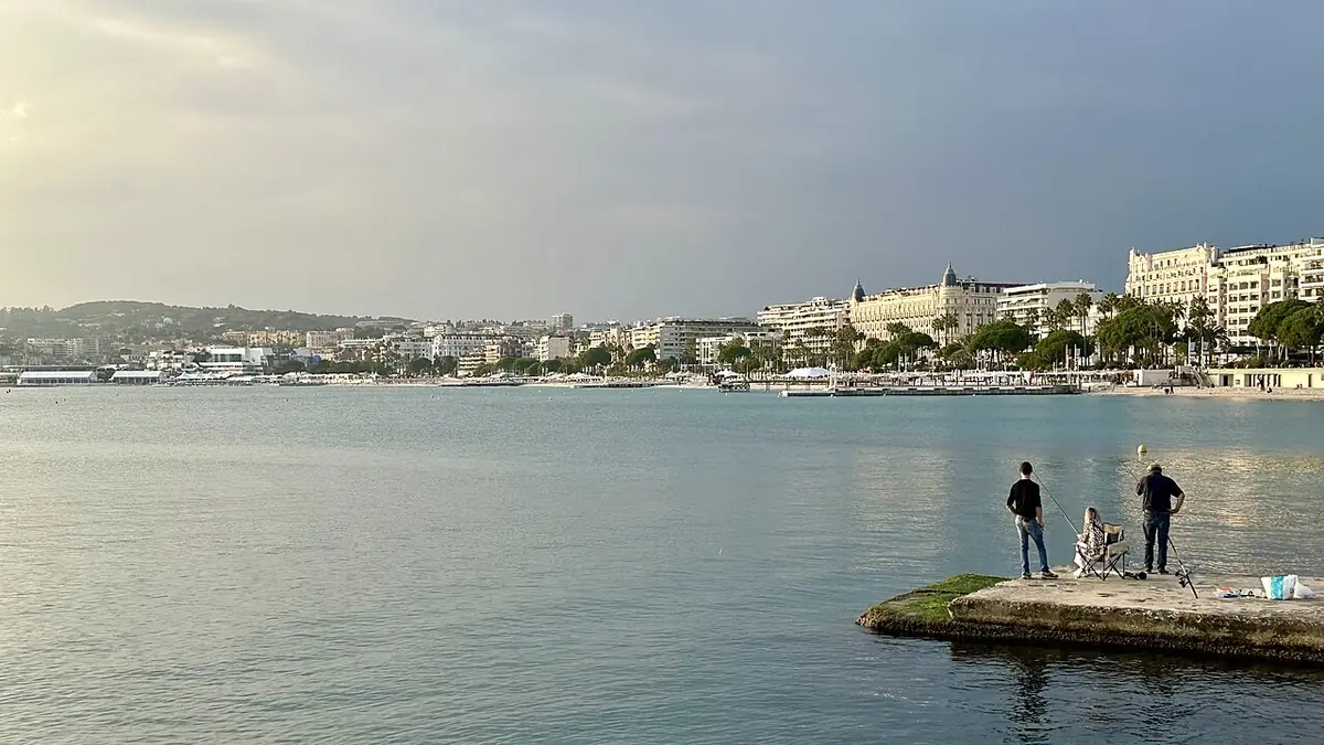 Pêcheurs sur le front de mer, silhouette de Cannes en arrière-plan