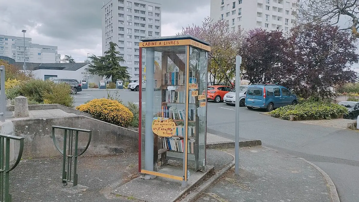 Une rue de Cholet bordée d’immeubles, avec boîte à livres à la Place Saint-Pierre