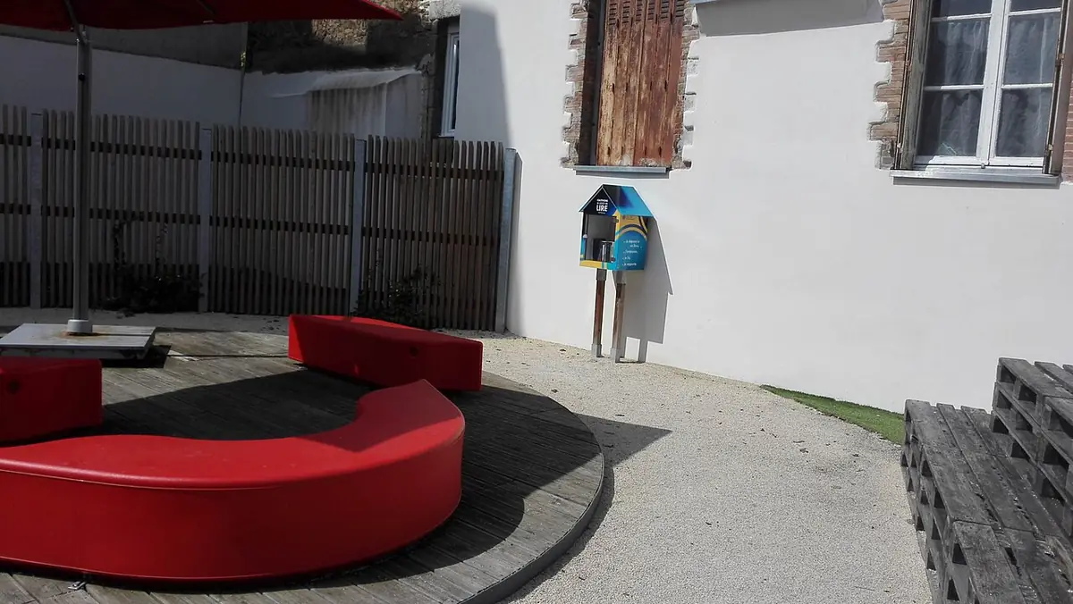 Une cour résidentielle à Cholet avec maison à volets et boîte à livres