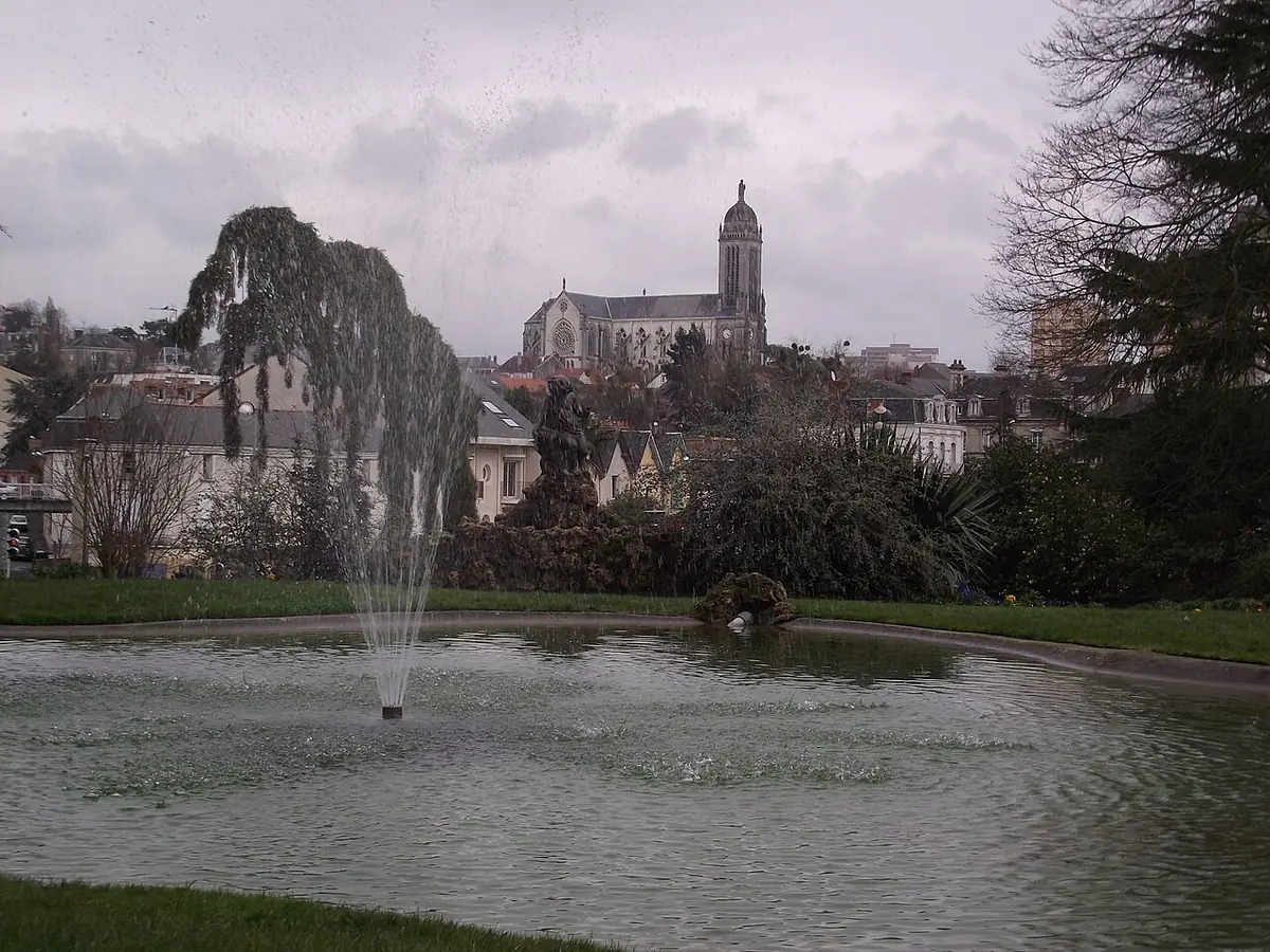 Un parc de Cholet avec fontaine, église et théâtre en arrière-plan
