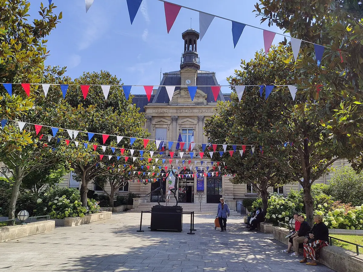 L’Hôtel de Ville de Clichy pavoisé de drapeaux, avec sa place arborée