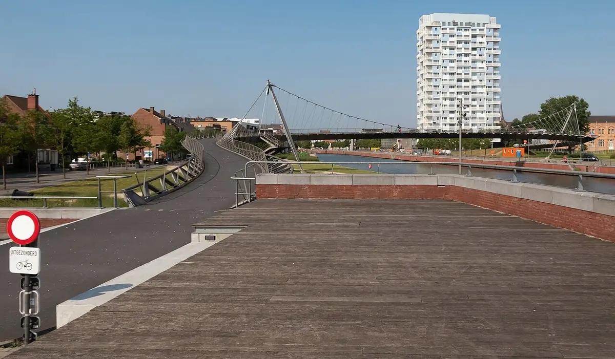 La Collegebrug, pont pour vélos au-dessus de la Lys, avec une tour d’habitation au fond