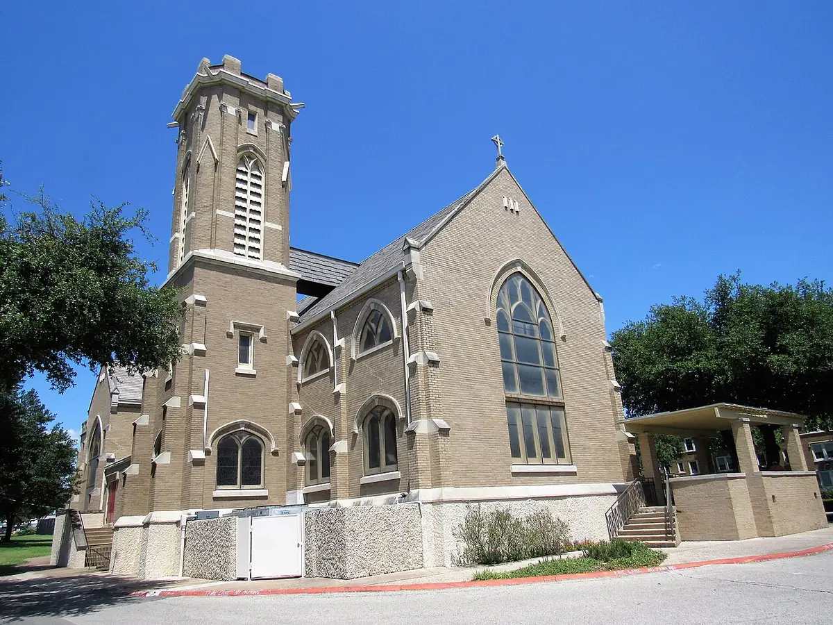 St. Matthew's Cathedral, a Gothic stone church with a single bell tower, under a clear Dallas sky