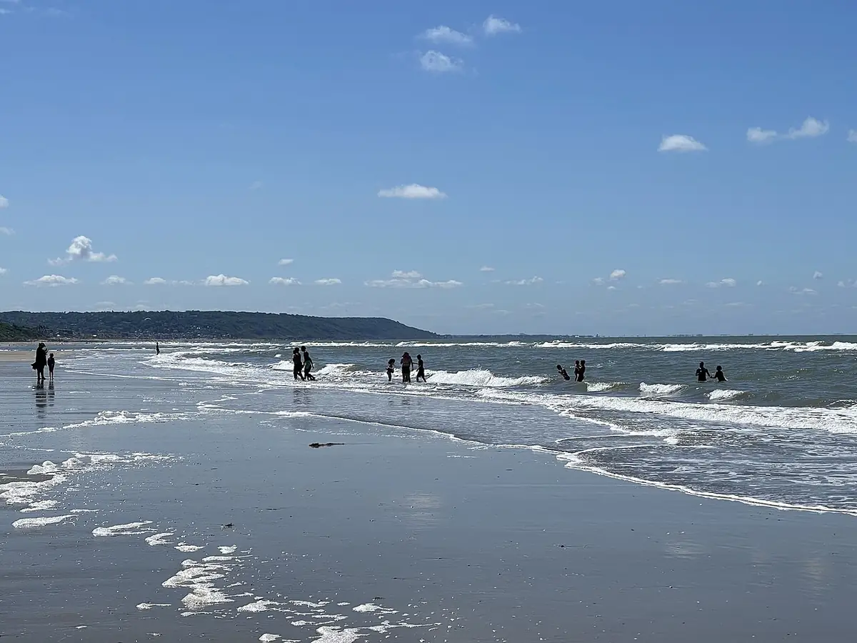 La plage de Deauville, baigneurs dans les vagues sous un ciel bleu