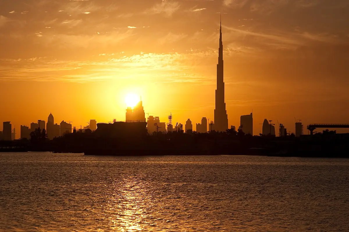 The sun setting behind Downtown Dubai's skyline, seen from the water