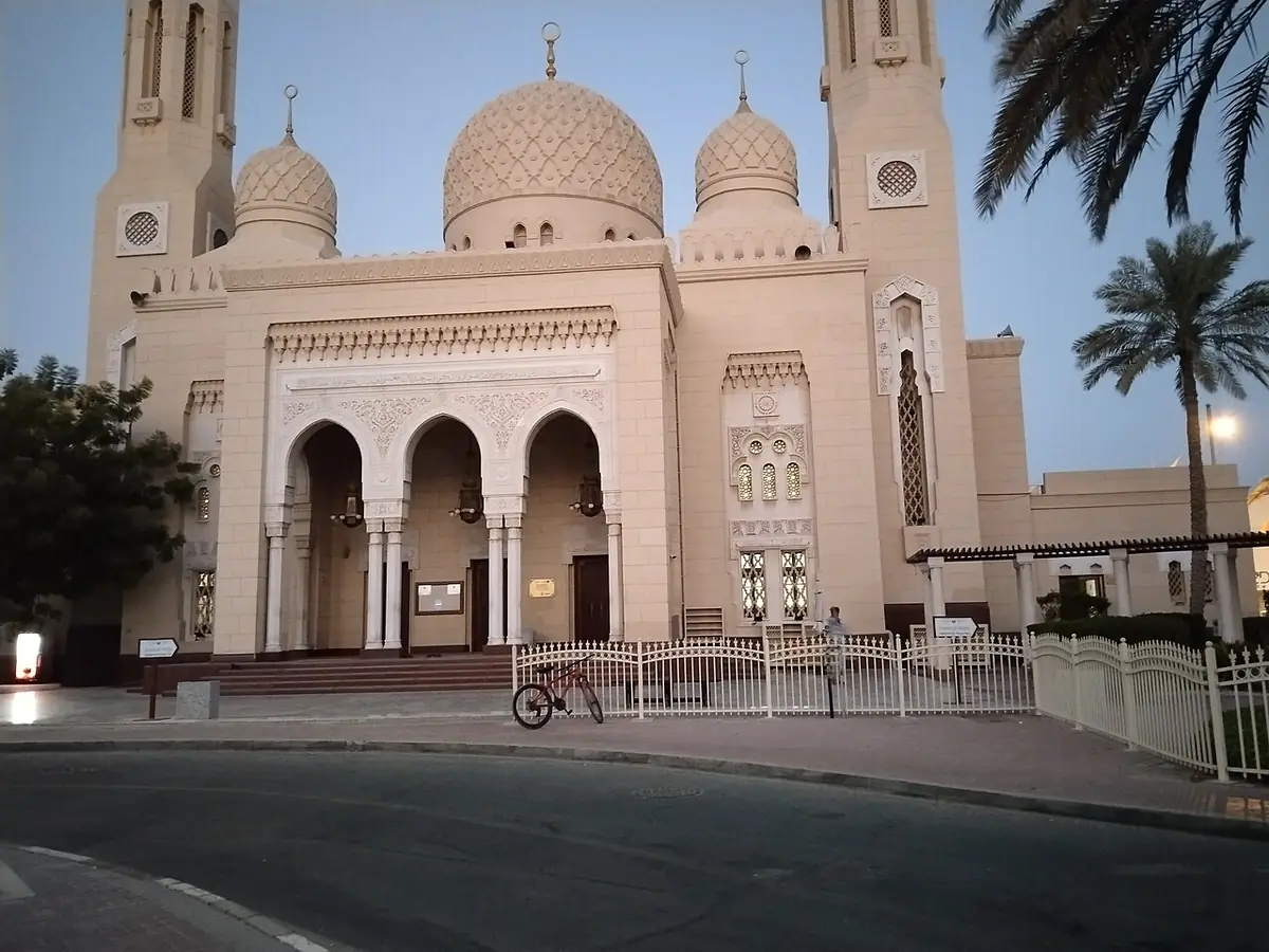 La façade en grès et le minaret de la mosquée Jumeirah, encadrés de palmiers sous un ciel dégagé