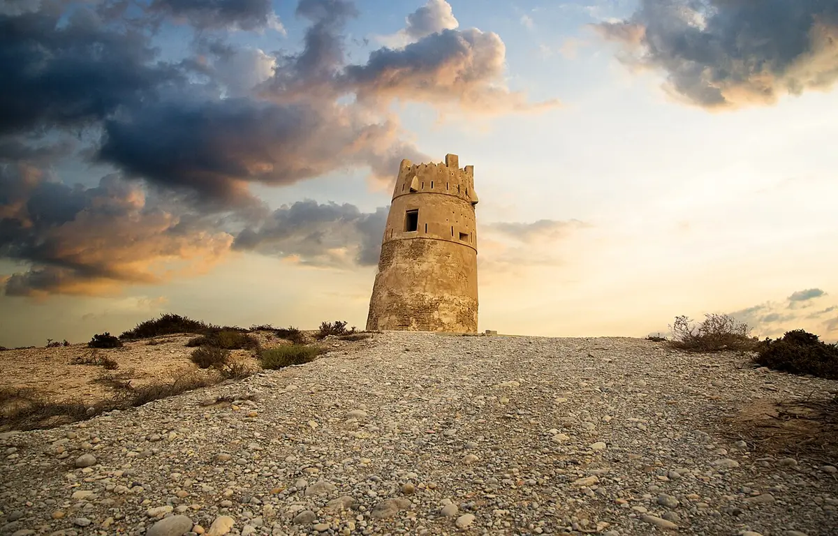 Al Hamra Tower silhouetted against a dramatic dusk sky