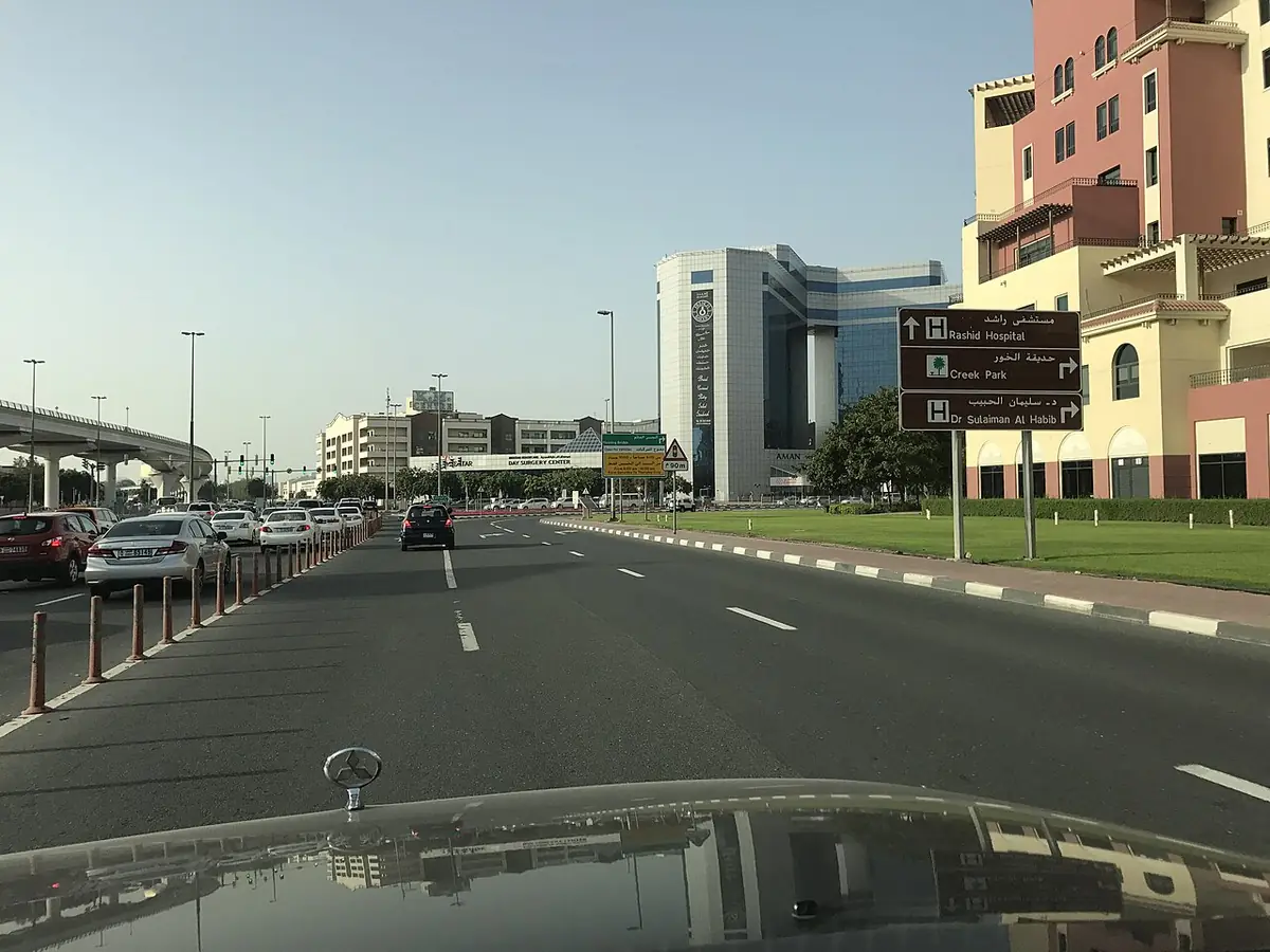 Une large rue calme à Dubaï, bordée d’immeubles de taille moyenne sous un ciel voilé