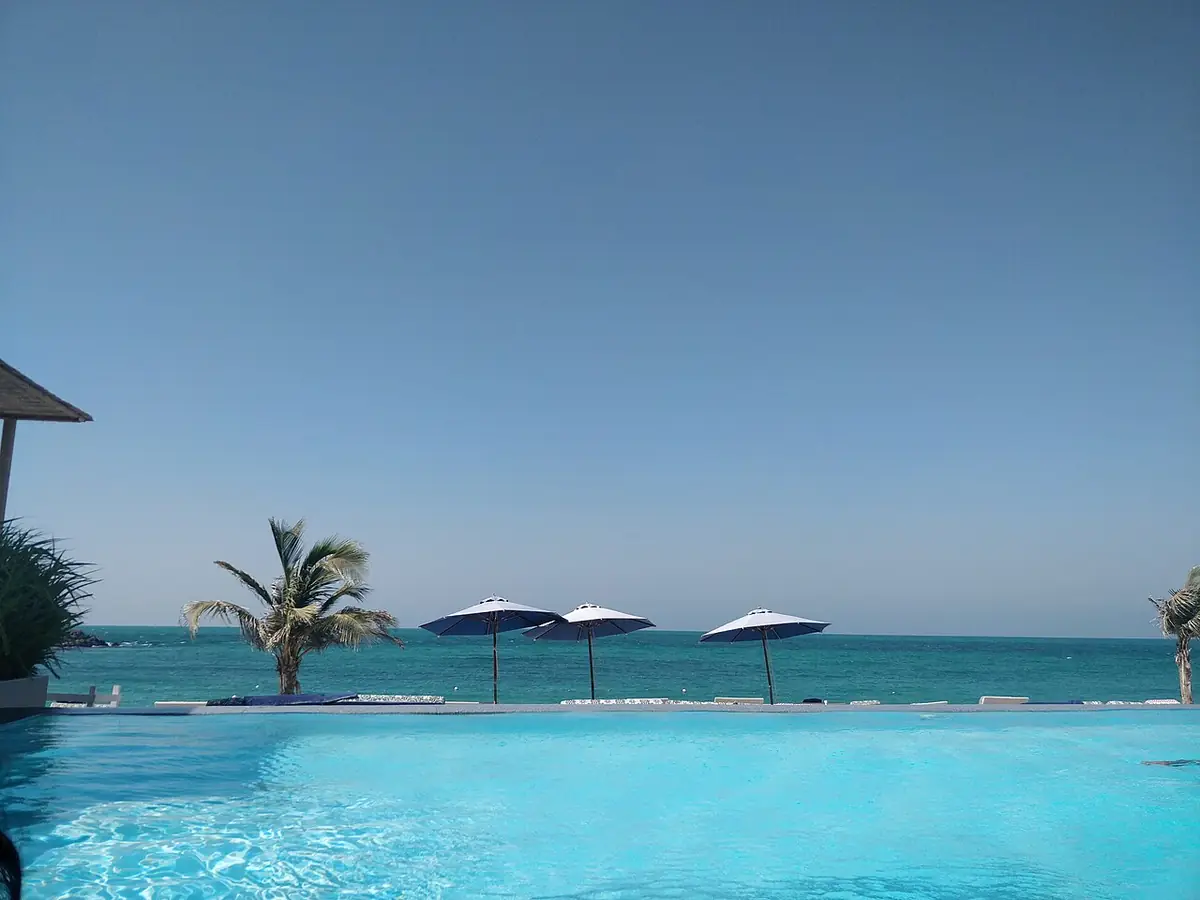 A pool overlooking the sea with palm trees and umbrellas on Zaya Nurai Island