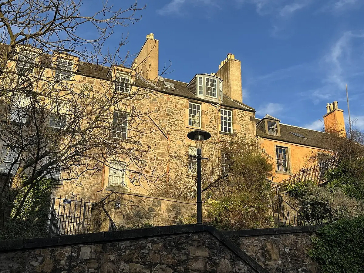 Maisons en pierre blonde au soleil sur Calton Hill à Édimbourg, arbres au premier plan