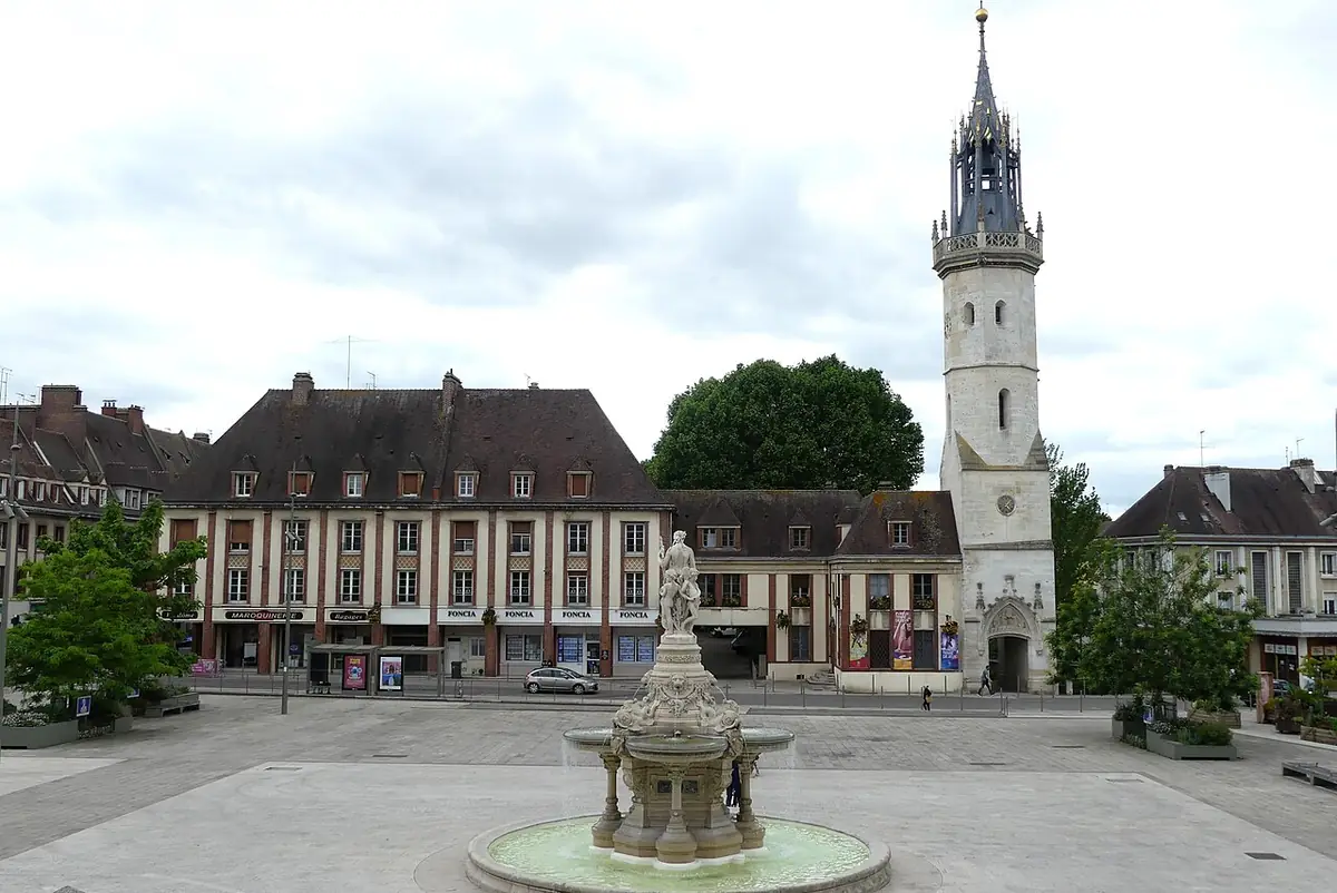 La tour de l’Horloge d’Évreux au-dessus d’une grande place pavée avec fontaine, bordée de façades