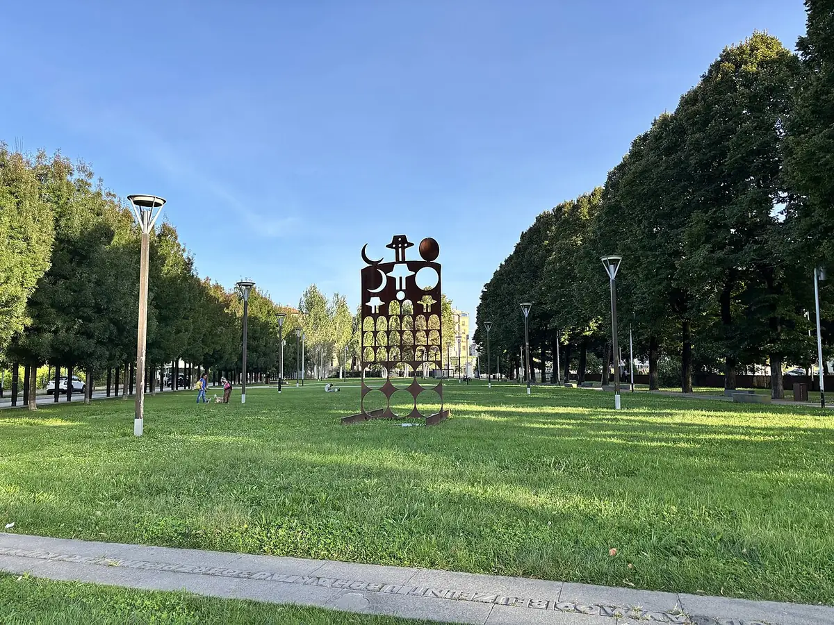 Pelouse bordée d’allées d’arbres devant le Teatro del Maggio à Florence, sculpture au centre
