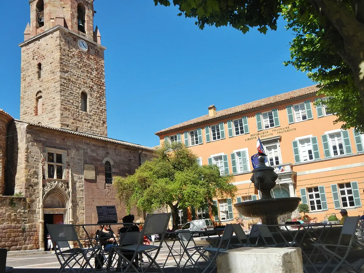 Clocher de la cathédrale de Fréjus au-dessus d’une place avec fontaine et terrasses