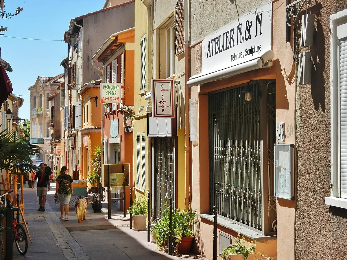 Rue étroite de Fréjus bordée de façades ocre, de plantes et de boutiques