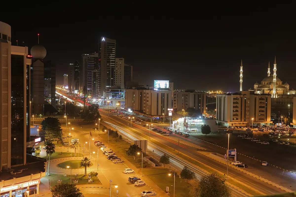 Une rue de Fujairah la nuit, avec la mosquée Cheikh Zayed illuminée au loin