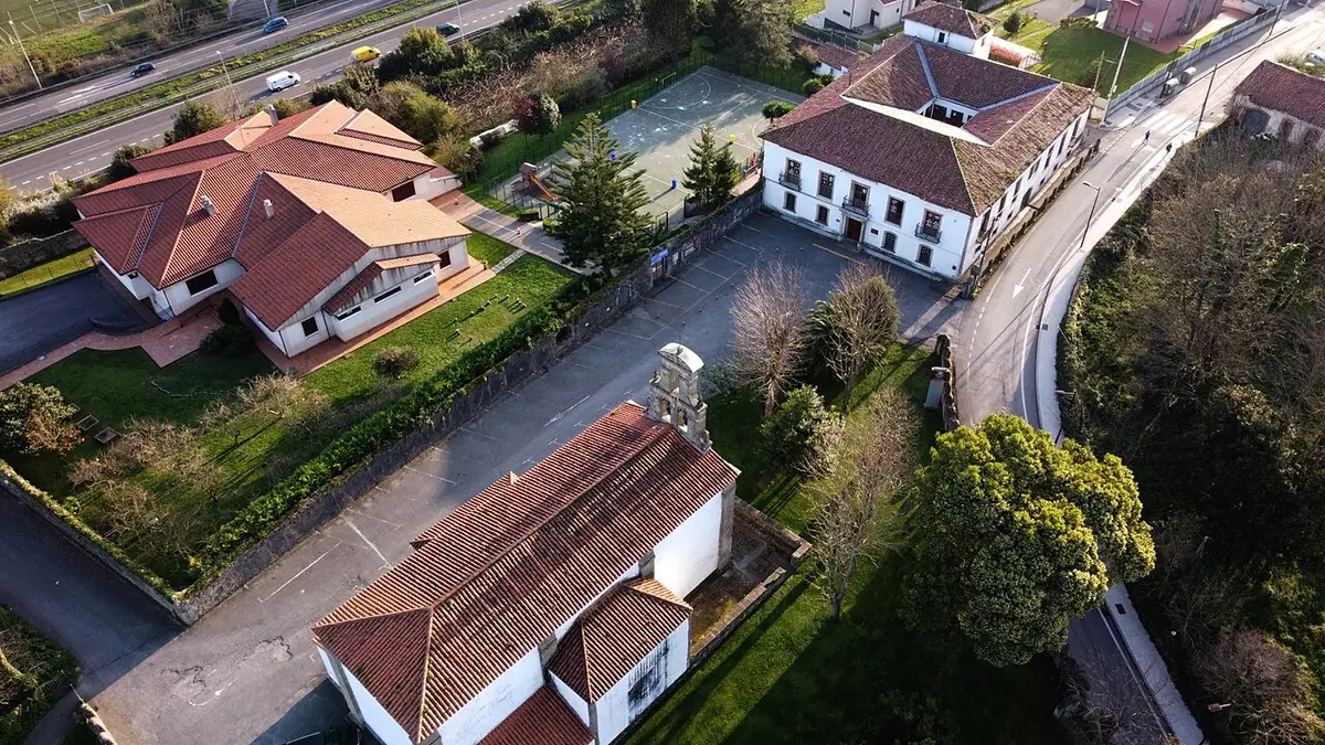 Vue aérienne de maisons aux toits de tuiles rouges entourées de jardins, à Gijón