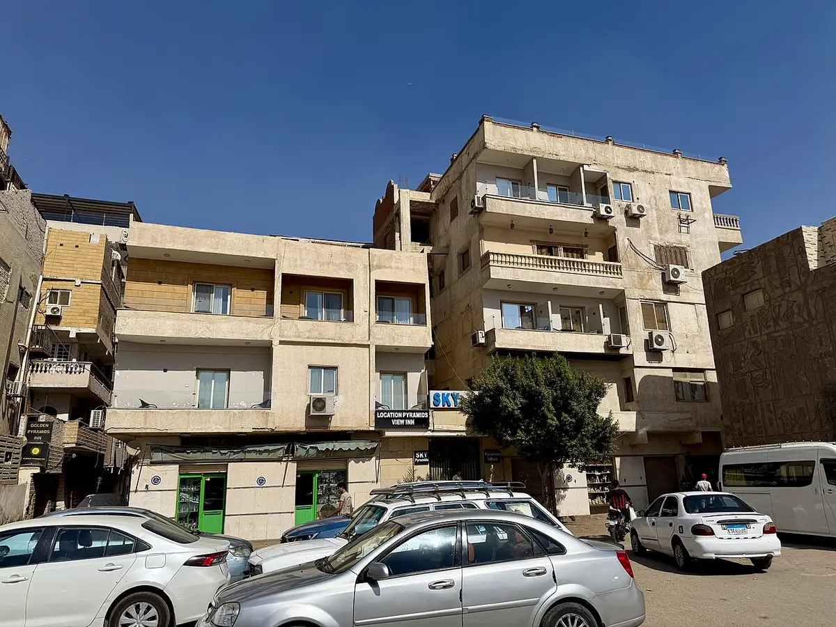 Un immeuble à plusieurs étages dans une rue de Gizeh, voitures stationnées le long du trottoir