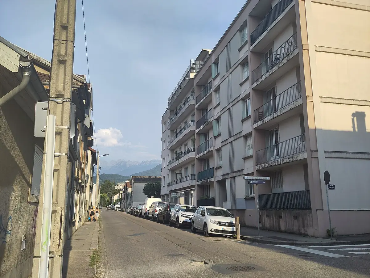 La rue Ponsard à Grenoble, immeubles et voitures stationnées, montagnes en toile de fond