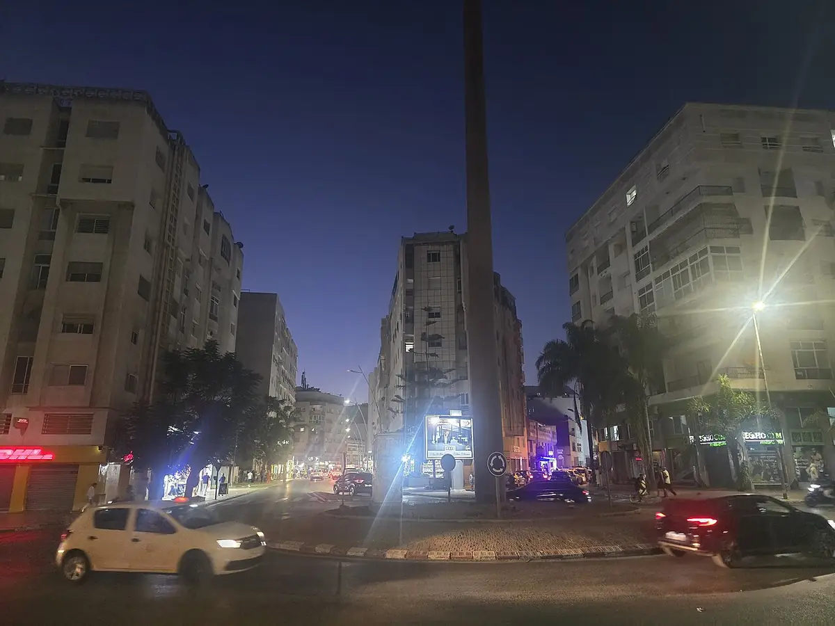 Une rue de Kénitra éclairée la nuit, bordée d’immeubles