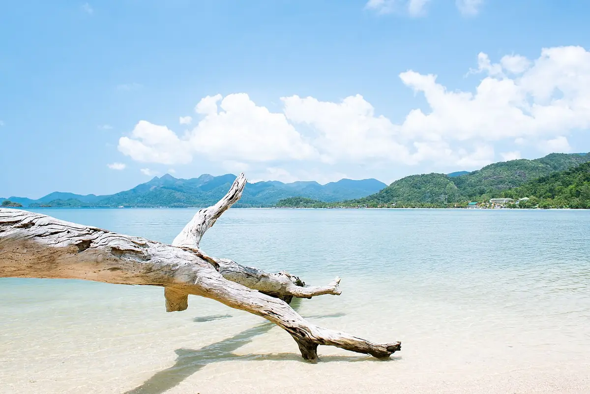 Une plage tranquille de Koh Chang, eau turquoise et collines en arrière-plan