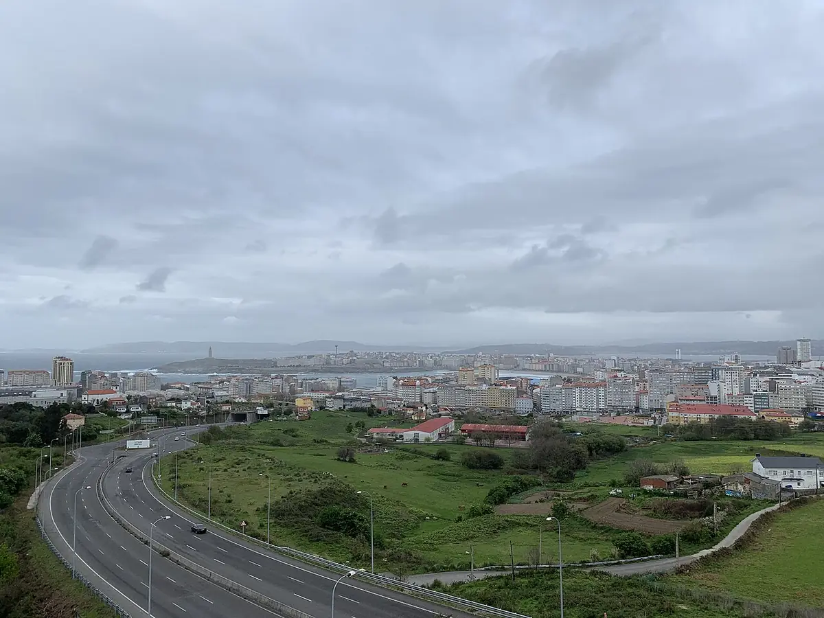Vue sur La Corogne et ses immeubles, avec une voie rapide et des champs au premier plan