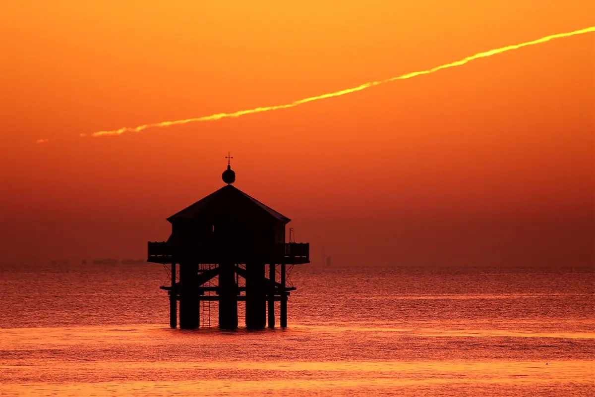Le phare du bout du monde en silhouette sur la mer au coucher du soleil