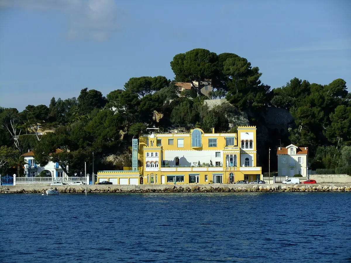 La villa Capriciosa, ancien casino jaune à Tamaris, au bord de l’eau devant une colline boisée