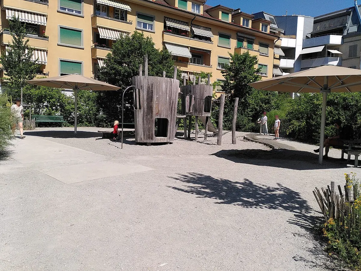 Une place avec structures en bois et bancs, entourée d’immeubles à Lausanne